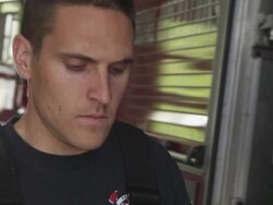 Handheld close-up shot of a fireman taking off his insulated coat. Stock Footage