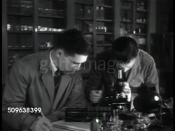 1941: FBI LABORATORY AT QUANTICO: VS FBI Agents working in lab, using microscopes, two Agents SOT talking about blood analyzed being in same group. Agent vacuuming clothing for spectrographic analysis. Agent working w/ microchemical analysis. Instructional Video