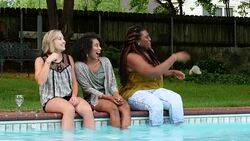 MS Laughing women sitting on edge of pool splashing friends during backyard party Stock Footage
