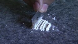 A drug user moves cocaine with a razor blade. Stock Footage