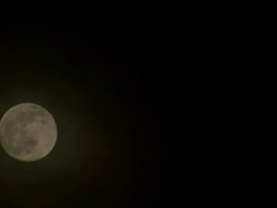 Low Angle static _ Dark clouds drift over the moon as it rises into the night sky  Stock Footage