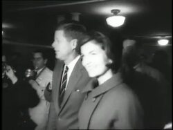 U.S. Senator John F. Kennedy  and wife Jacqueline walk toward a voting booth as photographers follow them. Stock Footage