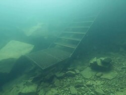 Diver swimmin along metal steps underwater Stock Footage