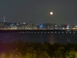 Night scenery of many buildings and Namsan Tower and rising of the moon in the sky from Han River Stock Footage