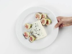 CU Woman hand entering setting down round white plate with hot dog, bun, relish and yellow dijon mustard / Omaha, Nebraska, United States Stock Footage