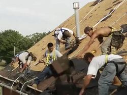 MS Five workers removing shingles on roof of red building / Chelsea, Michigan, United States Stock Footage