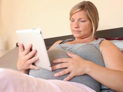 A young women using a technological device while pregnant. Stock Footage