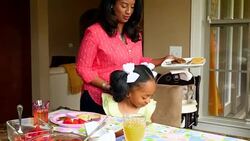 MS Smiling mother sitting down at breakfast table with young daughter Stock Footage
