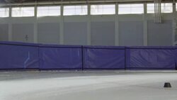 MS SLO MO Short track speed skater making turn with hand down on track in arena Stock Footage