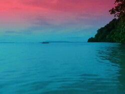 Indonesian canoe (prahu) crossing the blue ocean lagoon at sunset Stock Footage