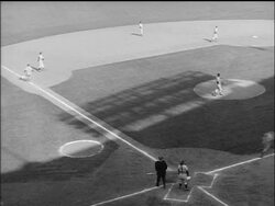 B/W 1955 man pitching, batter hitting ball + running to 1st base, man running from 3rd base to home Stock Footage