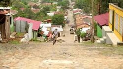 Teenager on bike speeds down steep cobblestone street Stock Footage
