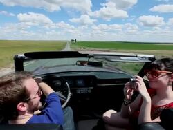 WS Young couple in convertible taking self portrait with digital camera while driving on rural road through grain fields/Washington, USA  Stock Footage