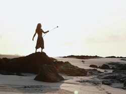 MS Rasta man wearing glasses standing on rock spinning poi balls with sunrise / Montezuma, Punteranes, Costa Rica Stock Footage