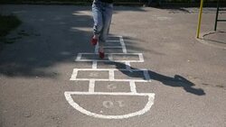 Slow motion shot of a young adult girl playing hopscotch outdoors Stock Footage