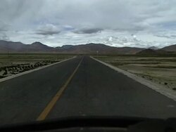 agricultural tractor driving on highway through tibetan plateau Stock Footage