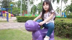 Cute girl is playing a toy at amusement park Stock Footage