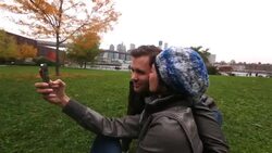 Young woman takes smartphone photo kissing boyfriend on cheek with New York skyline in background Stock Footage