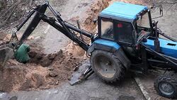 Man digging a trench while excavation vehicle standing by Stock Footage