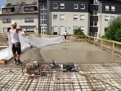 MS Shot of workmen working plastic overspread on floor at construction site / Hermeskeil, Rhineland Palatinate, Germany Stock Footage