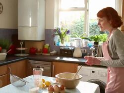 WS Shot of woman breaking eggs, sieving flour in bowl and mixing ingredients / London, Greater London, United Kingdom Stock Footage