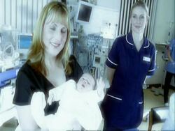 CU mother holding baby, nurse in background Stock Footage