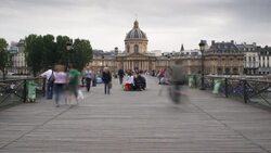 Pedestrians cross the Seine River on the Pont des Arts near the Institut de France. Stock Footage