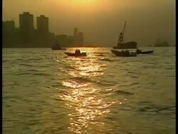 WA low angle view across harbour, boats bobbing on sunlit water, silhouetted buildings on horizon, Hong Kong Stock Footage