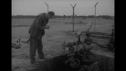 Middle Eastern town by water; oil tanker, pipelines, derrick in oil fields; maybe in 1940s News Clip