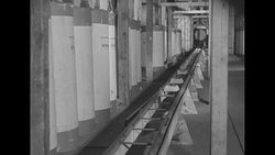 Warehouse workers unload rolls of paper and move them along 'miniature railroad' conveyor system News Clip