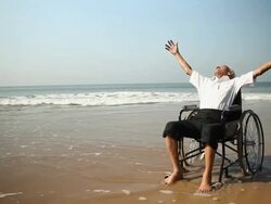 Senior man sitting on the wheelchair on the beach Stock Footage