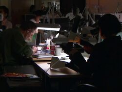 Gemcutters sit at their desks, looking through microscopes and writing, respectively. Stock Footage