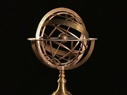 An armillary sphere slowly spins in front of a black background. Stock Footage