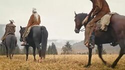 DS Two cowboys and a cowgirl riding across mountain Stock Footage