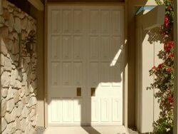 POV DS towards large paneled entry doors of mid-century modern home as one of the doors swings open Stock Footage