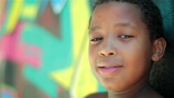 Brazilian boy looks at camera and smiles leaning against graffitied wall Stock Footage