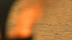 A flotilla of rowboats carries Diwali participants past a burning torch. Stock Footage