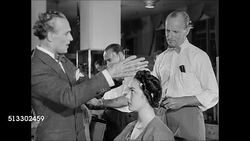 1945: HAIR STYLING: HD: Antoine de Paris Salon chairs w/ female clients having hair styled, Antoine walking through salon w/ hairstylists working, making suggestions, applying chignon to brunette woman's hair, asking her if she likes it. Instructional Video