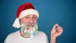 Adult senior man showing a copy space and showing the thumb in the Santa Claus hat on a blue background Stock Footage