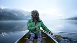 Senior Woman canoeing on a pristine lake Stock Footage