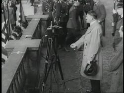 German Chancellor Adolf Hitler delivers a speech, then rides through a cheering crowd. News Clip