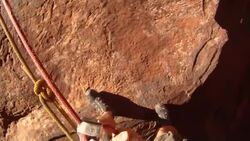 Close up of feet rappelling down edge of steep canyon cliff (POV) Stock Footage