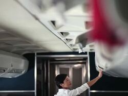 Air stewardess closing overhead lockers on aeroplane Stock Footage