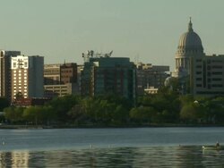 MS Man in canoe paddles past downtown skyline / Madison, Wisconsin, United States Stock Footage