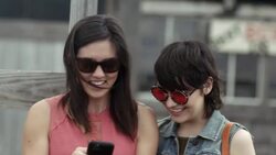 Two young women look at smartphone and laugh together in Texas ghost town Stock Footage
