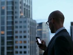 MS Businessman working on smart phone standing on deck looking out over cityscape at night/Seattle, Washington, USA Stock Footage