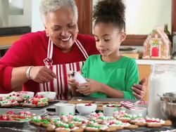MS Grandmother and Granddaughter Decorating Gingerbread Men Cookies in Kitchen / Richmond, Virginia, USA Stock Footage