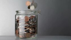 Coins falling into and overflowing jar Stock Footage