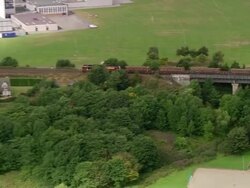 Aerial train traveling over viaduct / zoom out over the town of Stonehaven / Aberdeenshire, Scotland Stock Footage