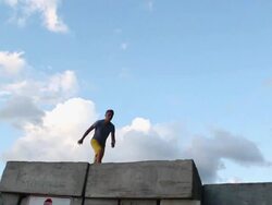 A young man jumping off a wall during sunset at the beach. - Slow Motion - Model Released - HD Stock Footage